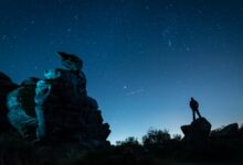 A plane passes by as a man stargazes at Brimham Rocks in Yorkshire as the Orionid meteor shower reaches its peak.